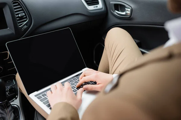 Vista recortada del hombre de negocios utilizando el ordenador portátil con pantalla en blanco en el coche - foto de stock