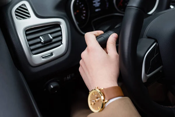 Cropped view of man with wristwatch using turn signal while driving car — Stock Photo