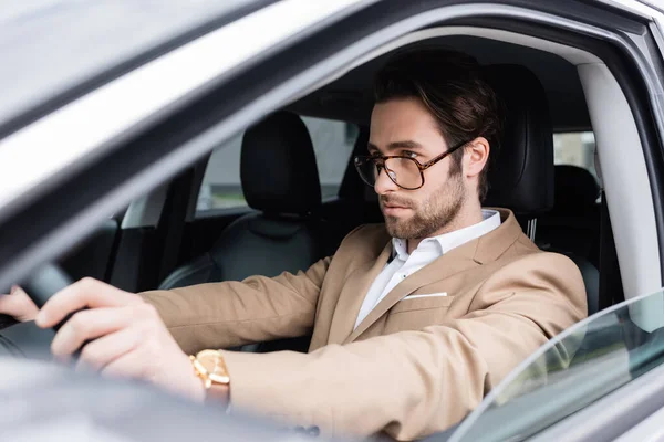 Uomo barbuto in occhiali guida auto moderna — Foto stock