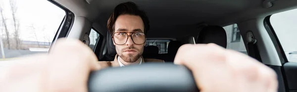 Uomo barbuto in occhiali con le mani sul volante con primo piano sfocato, striscione — Foto stock