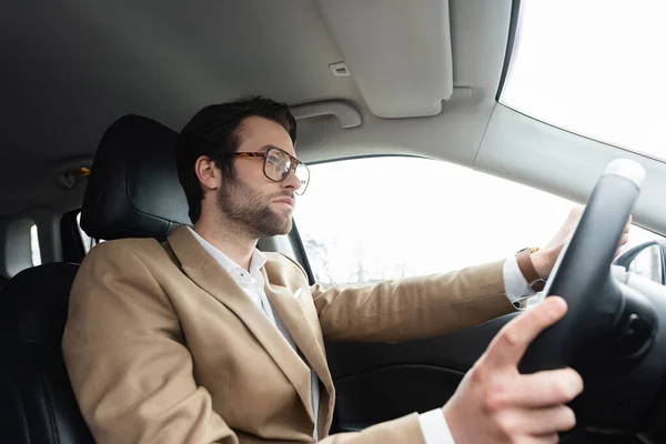 Homme barbu dans des lunettes de conduite voiture moderne — Photo de stock