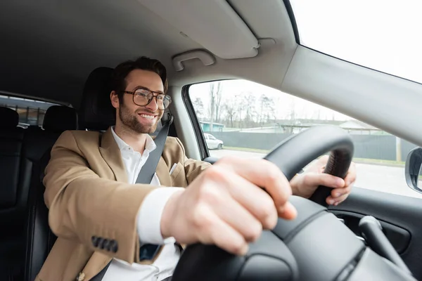 Homem barbudo sorridente em óculos dirigindo carro moderno — Fotografia de Stock