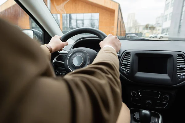 Partial view of man in beige jacket driving car — Stock Photo