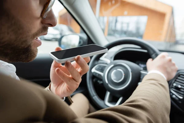 Visão parcial do homem barbudo gravando smartphone mensagem de voz durante a condução do carro — Fotografia de Stock