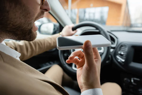 Vista recortada del hombre barbudo grabación de mensajes de voz smartphone mientras conduce el coche - foto de stock
