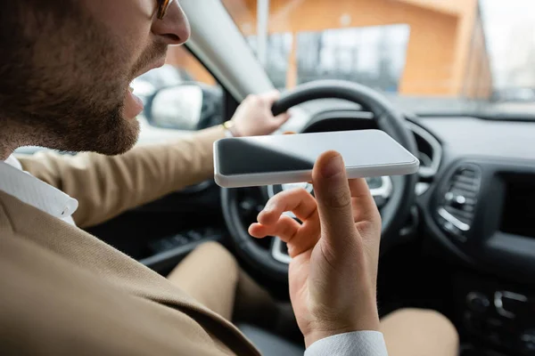 Cropped view of bearded man recording voice message smartphone while driving car — Stock Photo