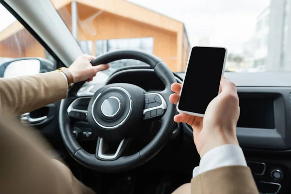 Обрезанный вид человека с помощью смартфона во время вождения автомобиля — стоковое фото