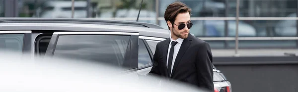 Bärtiger Geschäftsmann in Anzug und Sonnenbrille auf dem Parkplatz, Transparent — Stockfoto