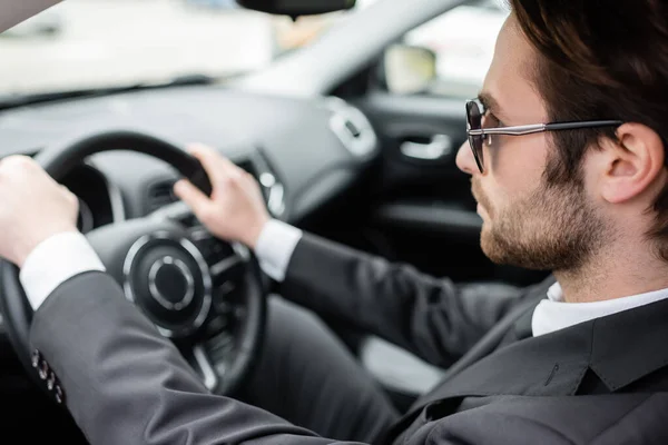 Бородатий чоловік в сонцезахисних окулярах за кермом сучасного автомобіля — стокове фото