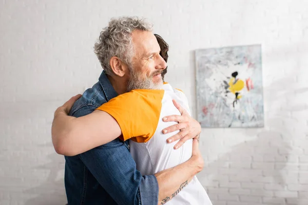 Mature father embracing son at home — Stock Photo