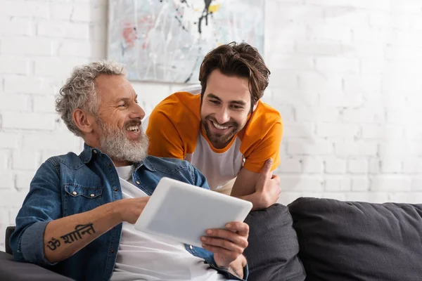 Reifer Mann benutzt digitales Tablet in der Nähe seines lächelnden Sohnes zu Hause — Stockfoto