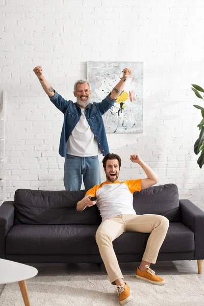 Père et fils excités regardant la télévision à la maison — Photo de stock