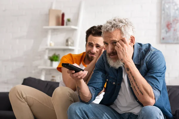 Worried man and blurred son watching tv at home — Stock Photo