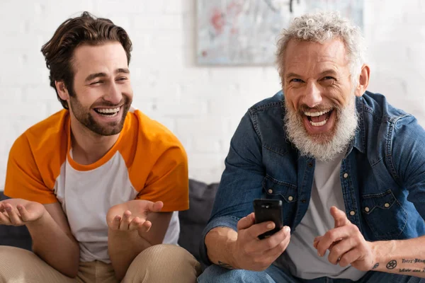 Happy mature man and son watching tv together — Stock Photo