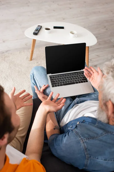 Overhead view of blurred son and father pointing at laptop — Stock Photo
