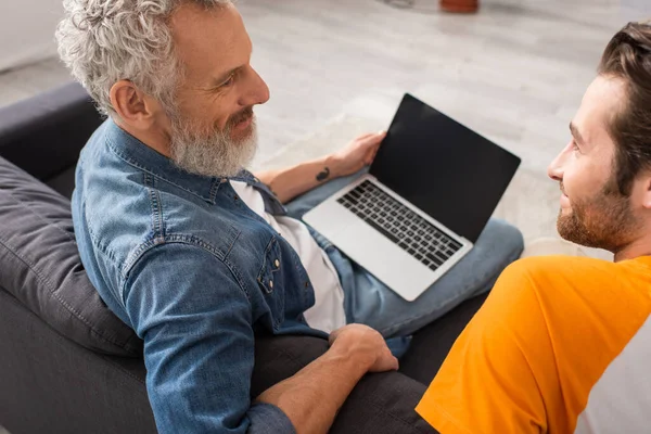 Älterer Mann lächelt Sohn fast verschwommen Laptop zu Hause an — Stockfoto