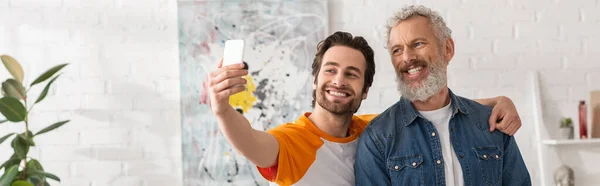 Fils souriant prenant selfie avec son père à la maison, bannière — Photo de stock