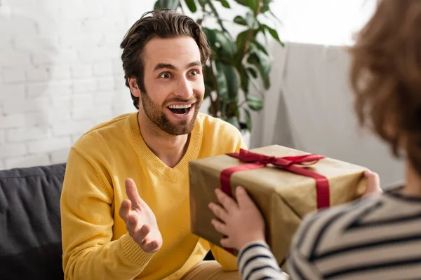 Веселий чоловік дивиться на розмитого сина з подарунком — стокове фото
