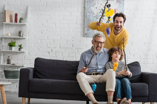 Happy parents with boy holding fishing rods with toy fishes — Stock Photo