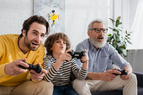 KYIV, UKRAINE - APRIL 12, 2021: Kid playing video game with parent and grandparent — Stock Photo