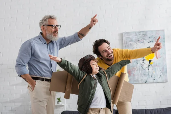 Smiling boy in aviator costume playing near parents — Stock Photo