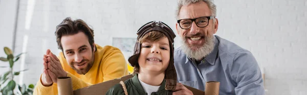 Ragazzo sorridente in costume da aviatore in piedi vicino ai genitori, striscione — Foto stock