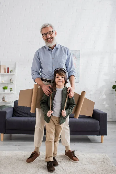 Smiling grandfather hugging kid in aviator costume — Stock Photo