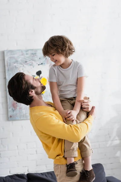 Junger Mann umarmt lächelnden Jungen zu Hause — Stockfoto