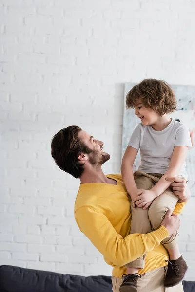 Un homme souriant embrassant son fils à la maison — Photo de stock