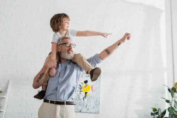 Sonriente abuelo y niño haciendo gestos en casa - foto de stock