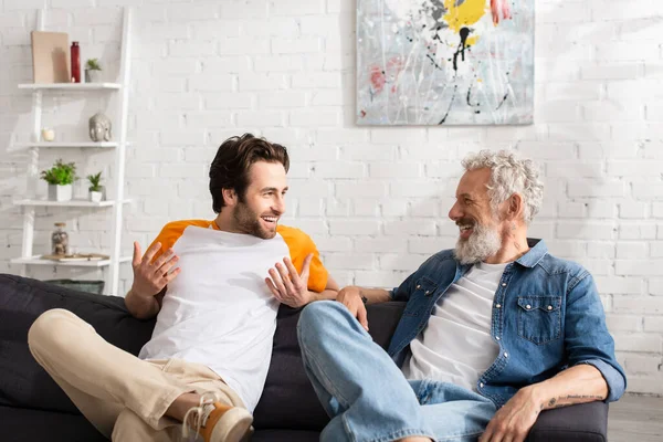 Joven hijo sonriendo mientras habla con el padre en casa - foto de stock