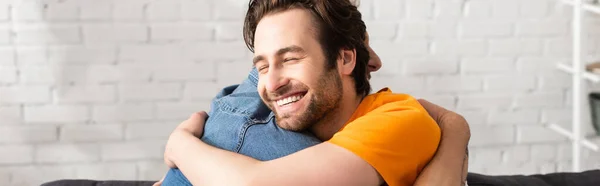 Hombre sonriendo y abrazando padre maduro, bandera — Stock Photo