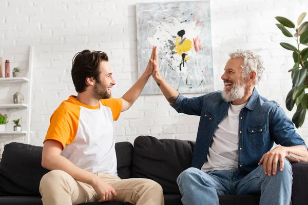 Joven y padre dando cinco en la sala de estar - foto de stock