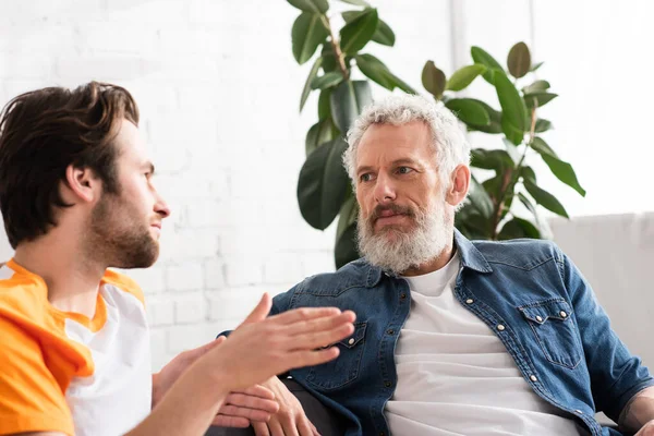 Verschwommener Mann spricht mit reifem Vater auf Couch — Stockfoto