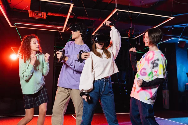 Aufgeregte interrassische Teenager zeigen Erfolgsgeste in der Nähe von Freunden in vr-Headsets — Stockfoto