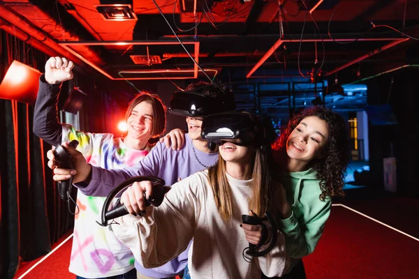 Happy interracial teens showing yes gesture near excited friends in vr headsets — Stock Photo