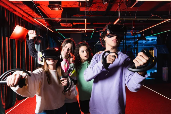 Smiling boy showing win gesture near excited interracial friends in vr game zone — Stock Photo
