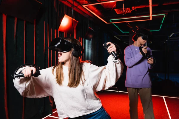 Stupito ragazza di gioco in auricolare vr vicino offuscata amico — Foto stock