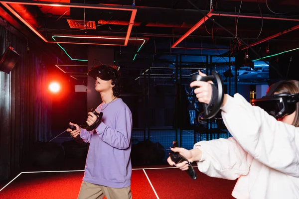 Astonished guy in vr headset gaming near friend in play zone — Stock Photo