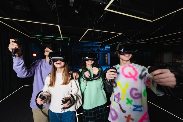 Amigos multiétnicos felices y sorprendidos divirtiéndose en la sala de juegos vr - foto de stock