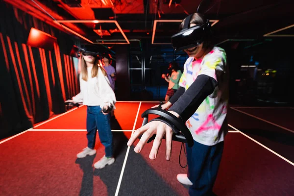 Cheerful boy in vr headset gesturing while gaming in vr play room with friends — Stock Photo