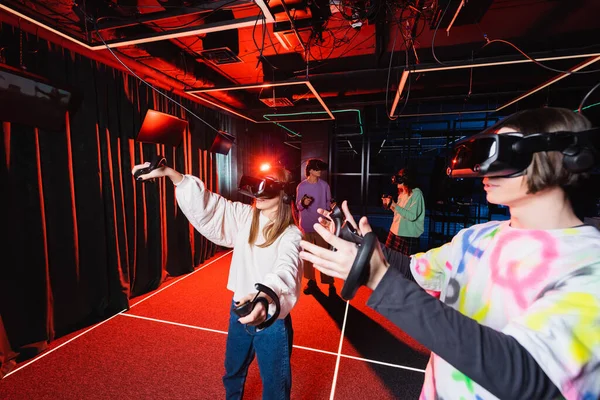 Amigos adolescentes se divierten en la zona de juego de realidad virtual - foto de stock