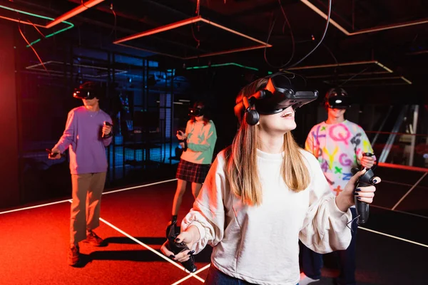 Astonished teenage girl gaming in vr headset near multiethnic friends — Stock Photo