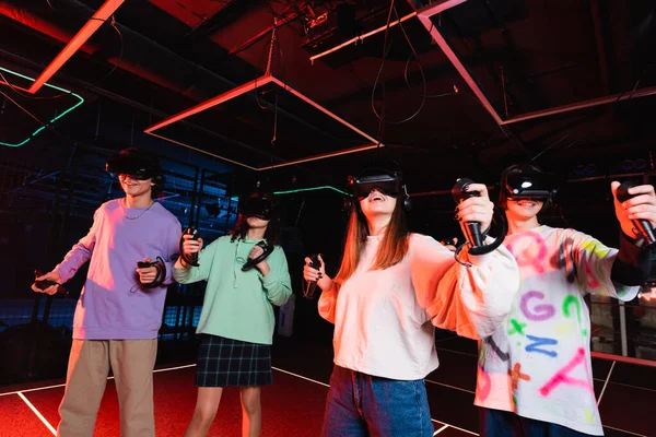 Amazed girl in vr headset gaming with smiling multicultural friends — Stock Photo