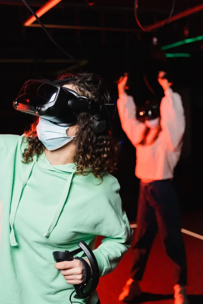 Afro-américaine fille jeu dans vr casque près de flou ami montrant geste de victoire — Photo de stock