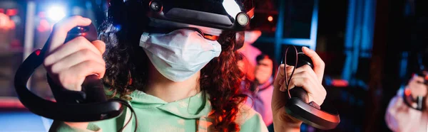 Vista recortada de chica afroamericana en juego de máscaras médicas en vr zona de juego, bandera - foto de stock