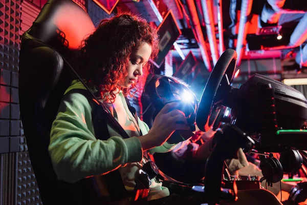 African american teenage girl holding vr headset on car racing simulator — Stock Photo