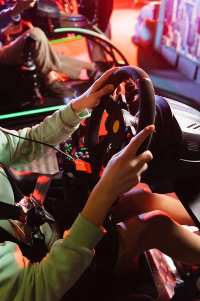 Vista parcial de los jugadores adolescentes jugando juegos de carreras en simuladores de coche - foto de stock