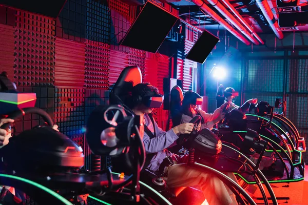 Teenagers in vr headsets playing racing game in car simulators — Stock Photo