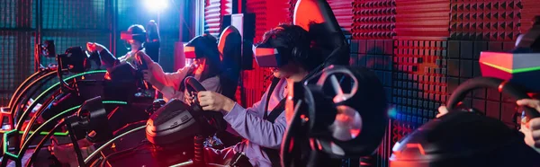 Teenage friends in vr headsets gaming on car racing simulators, banner — Stock Photo